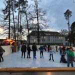 viele fröhliche Menschen fahren Schlittschuh auf einer Eisbahn