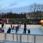 viele fröhliche Menschen fahren Schlittschuh auf einer Eisbahn